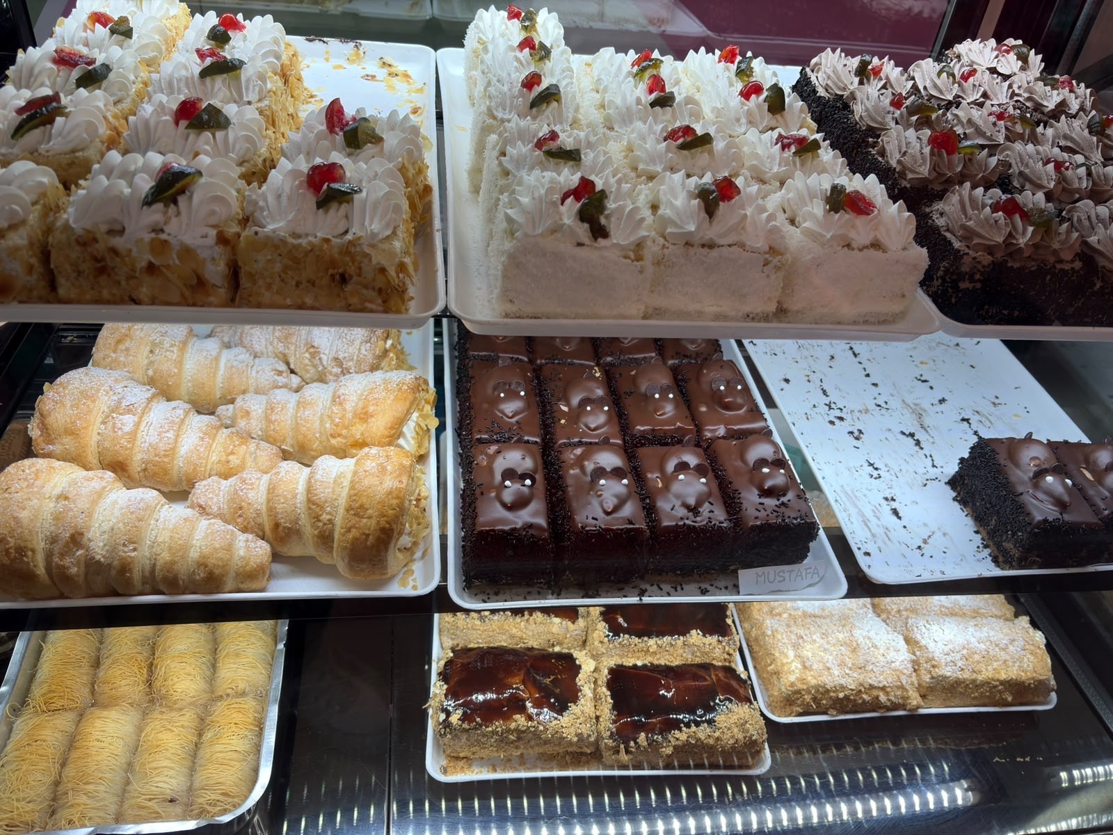Kuchenvitrine mit Sahneschnitten, Blätterteig-Röllchen, Schokoschnitten und Kadayif